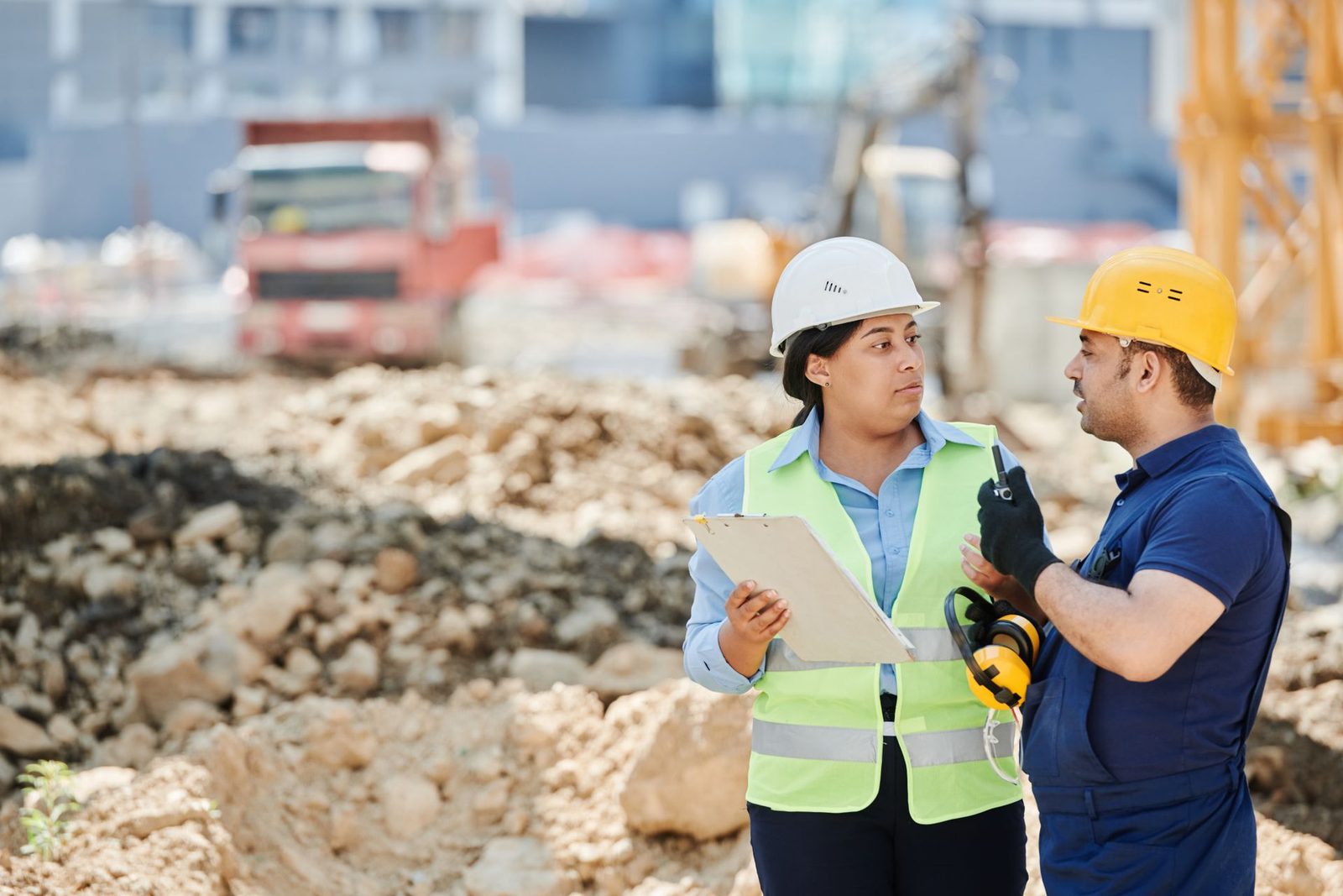 Two engineers in safety gear reviewing documents at a project site